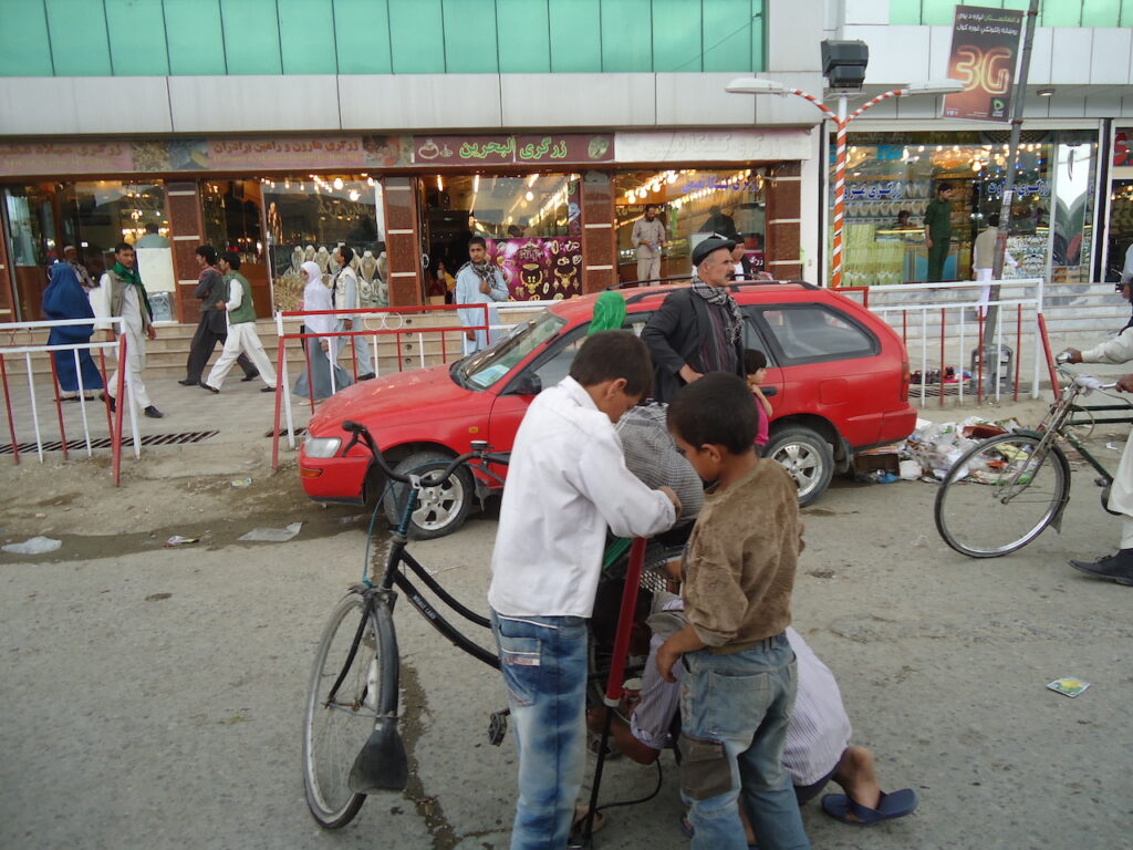 Three boys fixing a bike in Kabul