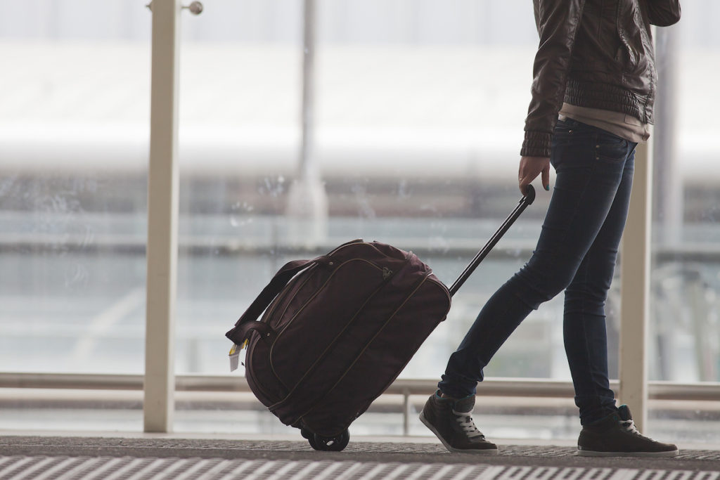 Traveler at airport with carry-on bag