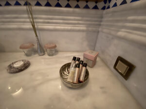 Silver bowl on a marble countertop containing bath amenities