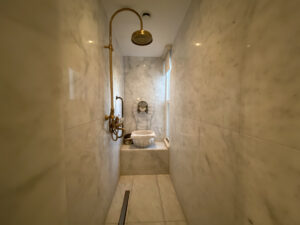 Marble hammam with gold showerhead and a window to the side