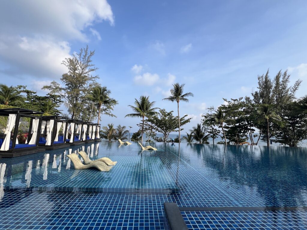 Large hotel pool with cabanas to the left and palm trees ahead