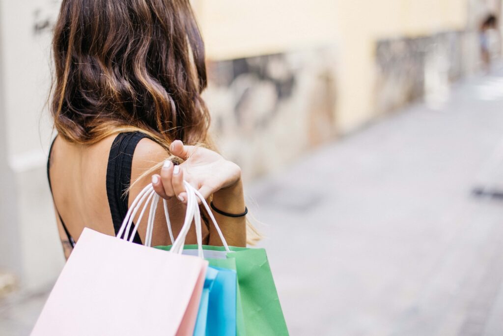 Woman holding multiple shopping bags behind her shoulder