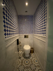 Bathroom with ornate tile work, toilet and a phone mounted on the wall