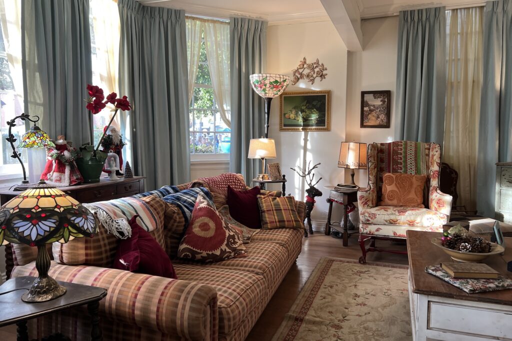 Lorelai Gilmore's cozy living room featuring a red couch with colorful pillow and blue curtains hanging in the window.