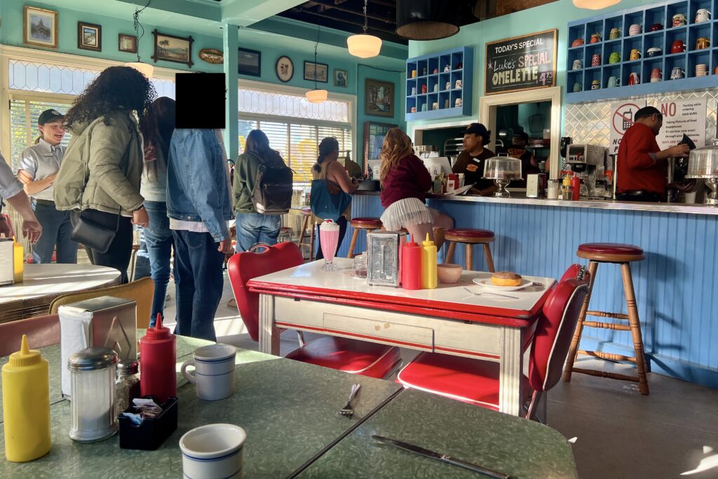 The interior of Luke's Diner from Gilmore Girls, with eclectic chairs, tables, and a counter.